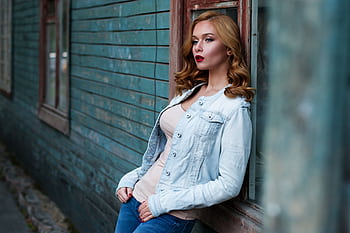 Stylish woman with red lipstick poses against a rustic wooden wall, exuding urban charm. HD wallpaper