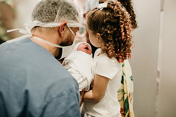 A happy family moment as a young girl meets her newborn sibling in the hospital. HD wallpaper