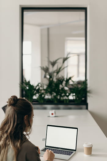 Woman working on a laptop in a modern home office with plants. HD phone wallpaper