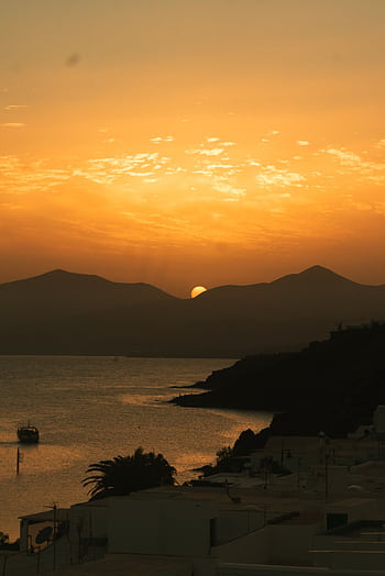 Stunning sunset view over a coastal landscape with silhouetted mountains and serene seas. HD phone wallpaper