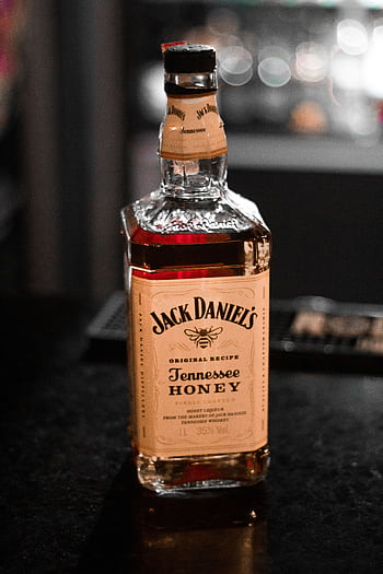 A close-up of a Jack Daniel's Tennessee Honey whiskey bottle on a bar counter. HD phone wallpaper