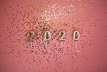 A festive pink background with 2020 candles and gold glitter, perfect for party themes. HD wallpaper