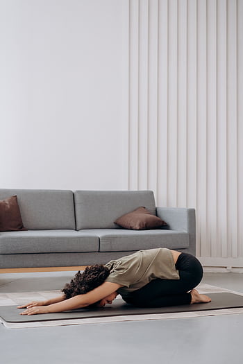 Young woman practicing yoga at home, fostering relaxation and inner peace in a serene living room setting. HD phone wallpaper