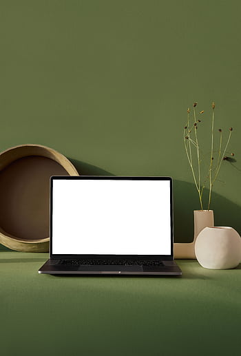 A modern workspace featuring a laptop with a blank screen, ceramic decor, and green background. HD phone wallpaper