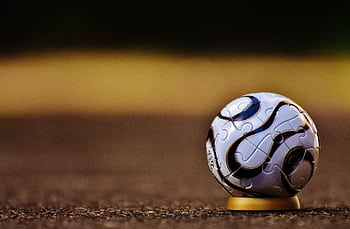 A close-up shot of a spherical puzzle ball placed on an outdoor surface, showcasing intricate patterns. HD wallpaper