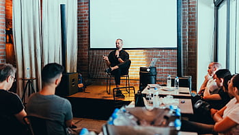 A business seminar with a speaker addressing an attentive audience in a modern conference setting. HD wallpaper