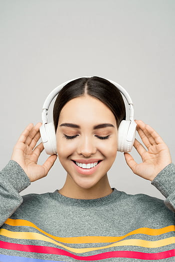 Young woman enjoying music with wireless heads and a joyful smile. HD phone wallpaper