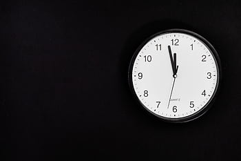 A simple wall clock set at midnight on a black background, ideal for business or time-related concepts. HD wallpaper