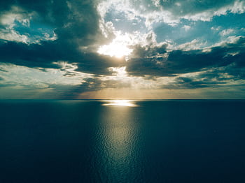 Peaceful ocean view with dramatic clouds at sunset creating a tranquil and serene seascape. HD wallpaper