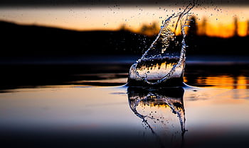 Dramatic water splash with sunset reflection creating a beautiful silhouette on the surface. HD wallpaper