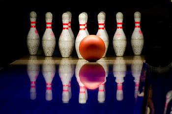 A striking close-up of a bowling ball approaching pins in a bowling alley. HD wallpaper