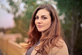 A young woman with long hair smiles confidently for an outdoor portrait session. HD wallpaper