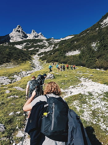 A group of hikers trekking through the rugged landscape of Garmisch-Partenkirchen, Germany under a clear blue sky. HD phone wallpaper