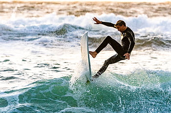 Energetic surfer performing a trick on ocean waves, showcasing skill and excitement. HD wallpaper