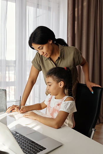 A mother helps her daughter with homework, highlighting education and family bonding indoors. HD phone wallpaper