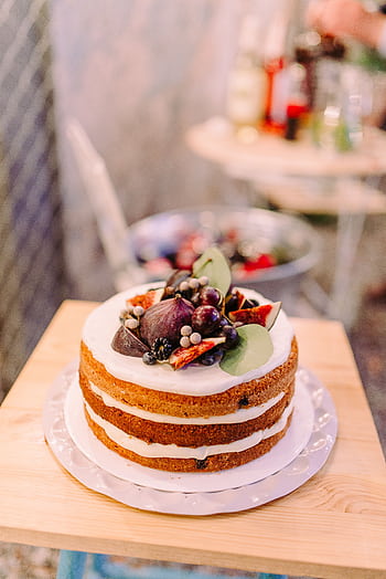 A minimalist fruit-adorned wedding cake on a wooden table, perfect for unique celebrations. HD phone wallpaper