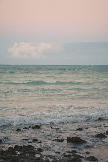 Serene beach scene at sunrise with calm waves and pastel colors, perfect for peaceful backgrounds. HD phone wallpaper