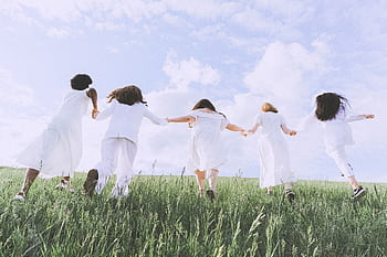 Five women joyfully running in a field under a clear sky, symbolizing dom and happiness. HD wallpaper