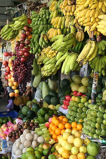 Vibrant arrangement of fresh tropical fruits at a local market, showcasing bananas, melons, and more. HD phone wallpaper