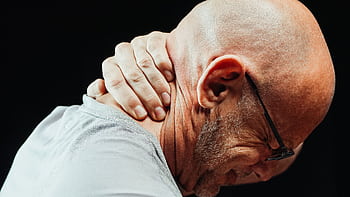 Side view of senior man holding neck with visible discomfort, highlighting neck pain relief. HD wallpaper