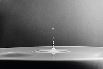 A high-definition macro shot capturing a water drop splash in black and white. HD wallpaper