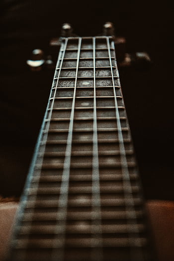 Artistic close-up of a guitar fretboard focusing on the strings and frets with a depth of field effect. HD phone wallpaper