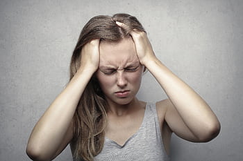 Young woman expressing stress and frustration while holding her head. HD wallpaper