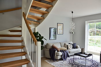Stylish Scandinavian living room featuring a wooden staircase, cozy sofa, and modern decor. HD wallpaper