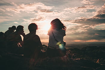 A group of people enjoy a breathtaking sunset view from a hilltop, creating serene silhouettes against the sky. HD wallpaper
