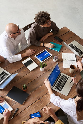 High angle view of a diverse team in a modern office setting discussing a business project. HD phone wallpaper