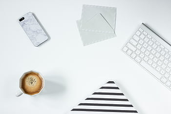 Clean minimalist workspace featuring coffee, keyboard, , and envelopes on a white desk. HD wallpaper
