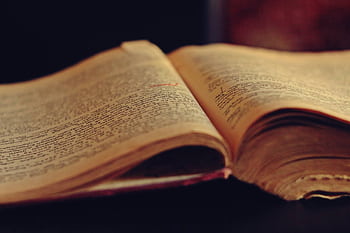A vintage open book displaying aged, yellowed pages with faded text. HD wallpaper