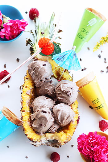 Delicious chocolate ice cream served in a hollowed pineapple, surrounded by vibrant summer decor. HD phone wallpaper