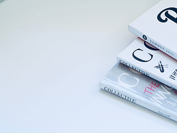 Stack of minimalist designed books on a clean white surface, perfect for creative concepts. HD wallpaper