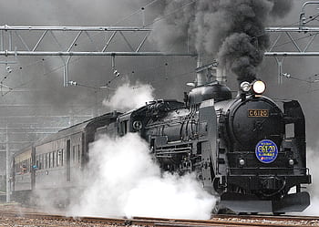 Steam locomotive releasing smoke and steam on a rail track, showcasing vintage train transportation. HD wallpaper
