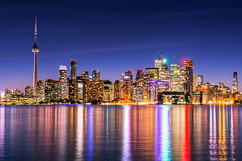 Illuminated Toronto skyline with CN Tower reflecting on calm water under a clear night sky. HD wallpaper