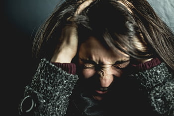 Close-up of a woman in distress with eyes closed and hands in hair, expressing anxiety. HD wallpaper