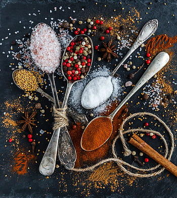 Assorted spices and seasonings arranged creatively on a dark surface, showcasing culinary art. HD phone wallpaper
