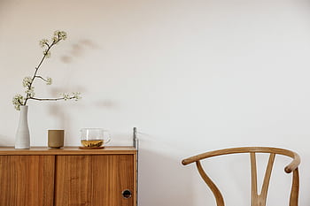A minimalist room featuring a wooden chair and table, perfect for modern home decor. HD wallpaper