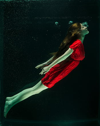 A woman in a red dress gracefully floats underwater, capturing a dreamlike essence. HD phone wallpaper