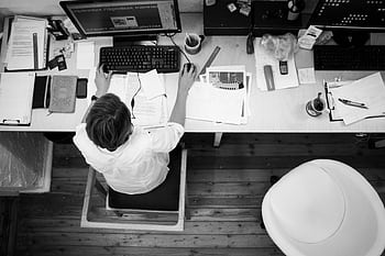 Black and white of an employee working at a desk with papers and computer. HD wallpaper