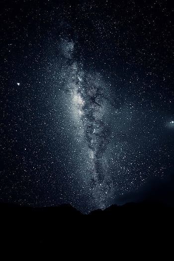 Captivating view of the Milky Way galaxy with a mountain silhouette under a starry night sky. HD phone wallpaper