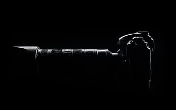 Artistic side profile of a DSLR camera with lens in dark setting. HD wallpaper