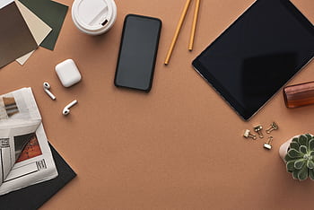 Top view of a stylish workspace with technology gadgets and stationery items on a brown background. HD wallpaper