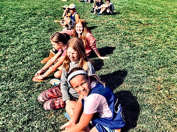 Group of children sitting in a grassy park, enjoying a sunny summer day together. HD wallpaper