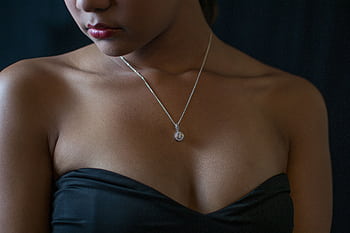 Close-up portrait of a woman wearing a diamond necklace and black dress, embodying elegance and style. HD wallpaper