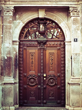 Intricate carved vintage wooden door with detailed arch and decorative elements. HD phone wallpaper