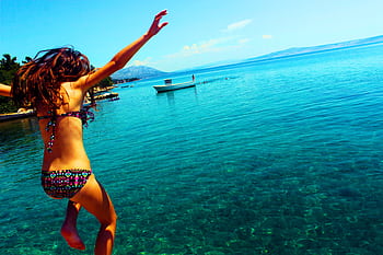 Young woman in a bikini jumps into crystal clear Croatian sea, enjoying summer vacation. HD wallpaper