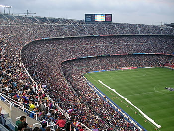 A packed stadium with enthusiastic fans watching an exciting soccer match. HD wallpaper