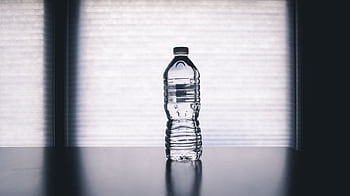 Stylish of a clear plastic water bottle on a reflective surface with a soft shadow. HD wallpaper